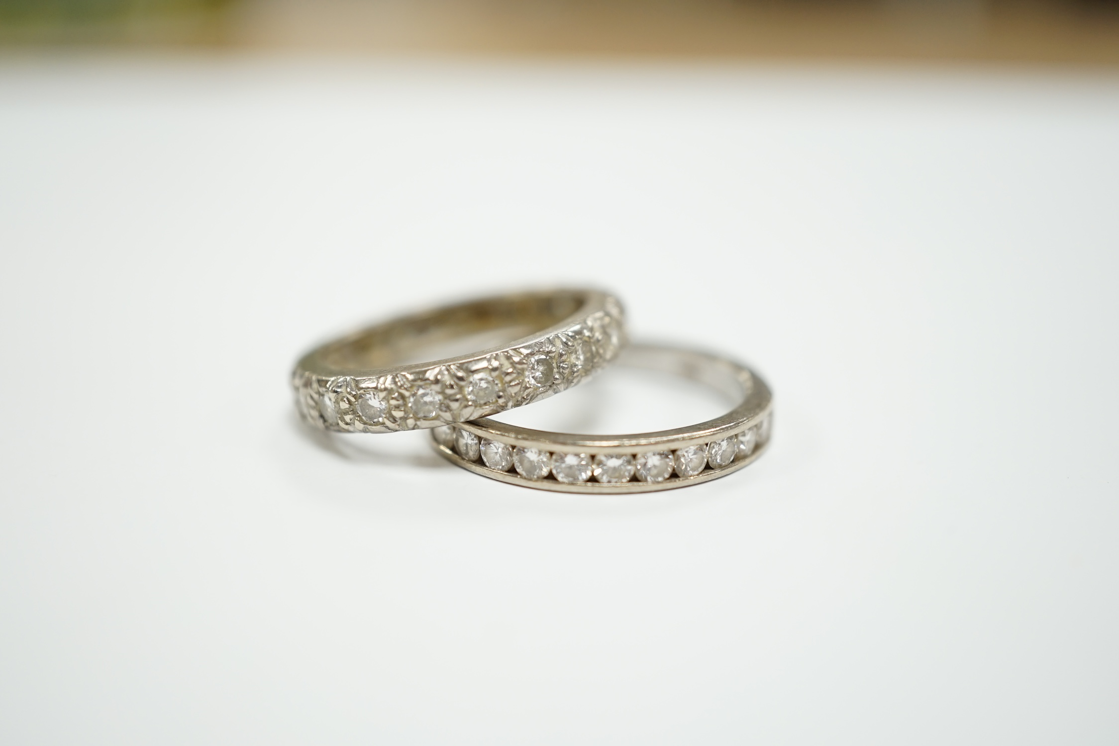 A white metal and diamond chip set full eternity ring, size L and a modern 18ct white gold and channel set diamond half eternity ring, size N/O.